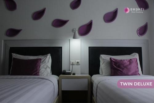 two beds in a hotel room with purple hearts on the wall at Shakti Hotel Bandung in Bandung