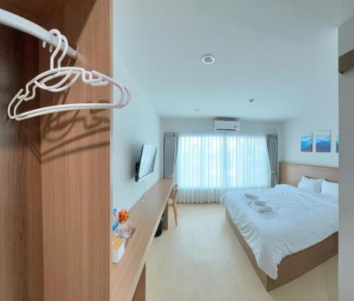 a bedroom with a bed and a desk with a television at Pingchan Hotel Soidao in Ban Phra Trong