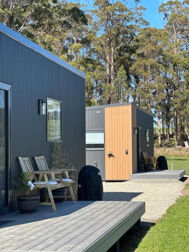 a building with two chairs and a wooden deck at Badger's View Farmstay GREEN HORNET Cabin in Railton