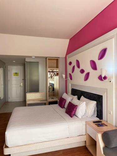 a bedroom with a large bed with purple walls at Shakti Hotel Bandung in Bandung