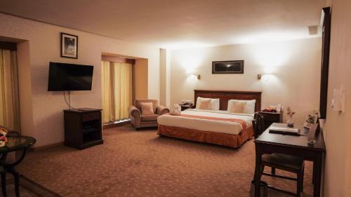 a hotel room with a bed and a desk and a television at MGM Mark Whitefield in Bengaluru