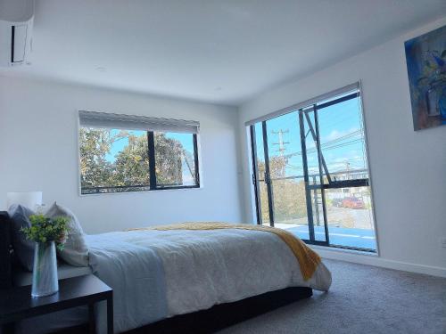 a bedroom with a bed and a large window at Stylish Family Retreat in Hillcrest 4 Bedroom and Playroom in Auckland