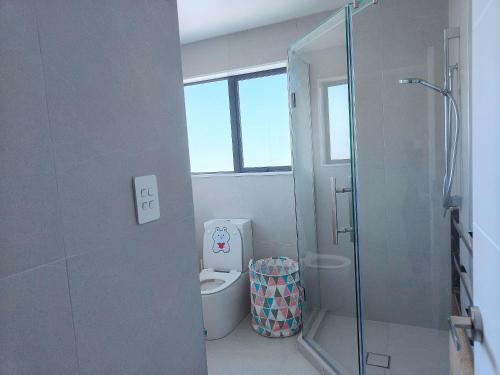 a bathroom with a toilet and a glass shower at Stylish Family Retreat in Hillcrest 4 Bedroom and Playroom in Auckland