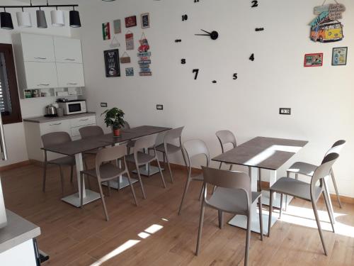 a dining room with tables and chairs and a clock on the wall at COMIDA Guesthouse & Experiences in Tortolì