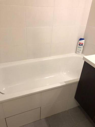 La salle de bains est pourvue d'une baignoire blanche et d'une bouteille de shampoing. dans l'établissement Le Fronton - Confortable T2 - Piscine, à Toulouse
