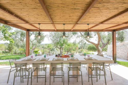 una mesa y sillas bajo una pérgola de madera en TD Trulli Amabilia Design Luxury Trulli with Pool, en Ostuni