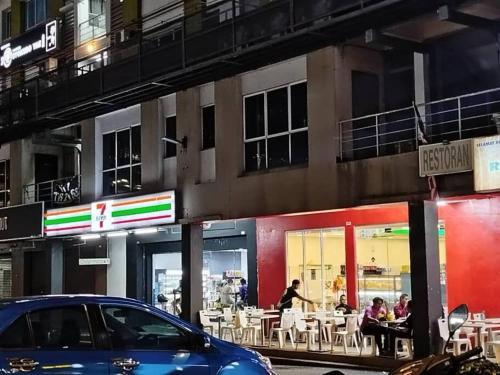 a blue car parked in front of a restaurant at Cozy Haven Queen Deluxe Studio 3 WI-FI Netflix in Petaling Jaya
