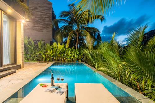 a pool with a table and chairs next to a house at Coco villa in Hoi An
