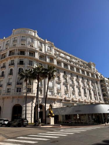 un grand bâtiment blanc avec un palmier en face dans l'établissement Residence Palais Miramar, à Cannes
