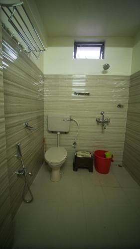 a bathroom with a toilet and a red bucket at Ha Sharing in Shillong