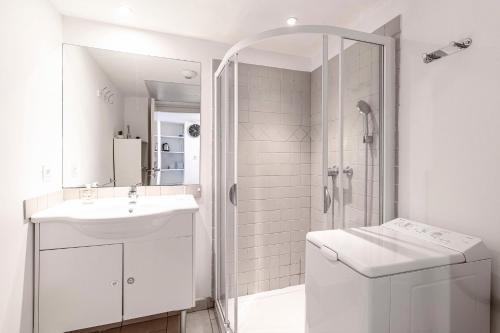 une salle de bain blanche avec un lavabo et une douche dans l'établissement La Marina - Appt climatisé pour 4, à Sari-Solenzara
