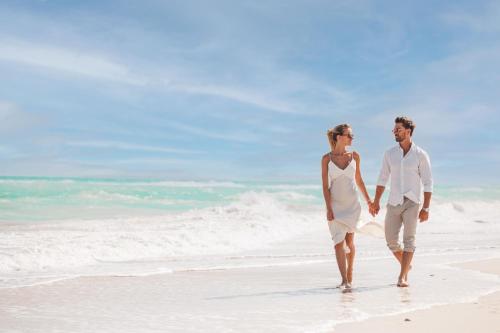 a man and a woman walking on the beach at The St. Regis Saadiyat Island Resort, Abu Dhabi in Abu Dhabi