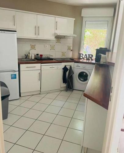 une cuisine avec des armoires blanches et une machine à laver dans l'établissement Le 10 Blagnac - Confortable T2 - Aéroport & Airbus, à Blagnac