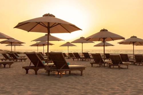 a group of chairs and umbrellas on a beach at The St. Regis Saadiyat Island Resort, Abu Dhabi in Abu Dhabi