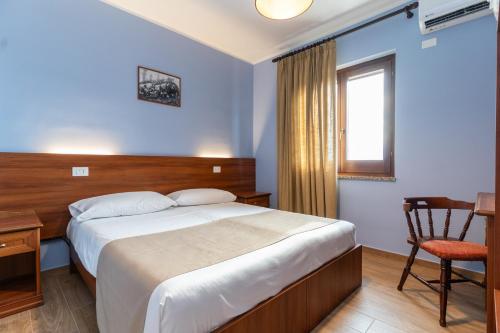 a bedroom with a bed and a desk and a window at B&B Gusto West in Bisignano