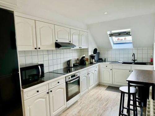 une cuisine avec des armoires blanches et un comptoir noir dans l'établissement Botti Sacre - Reims pétillant, à Reims