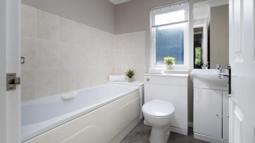a bathroom with a tub and a toilet and a sink at Newby Bridge Country Caravan Park in Newby Bridge