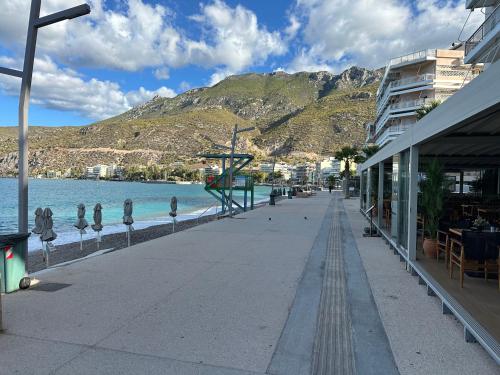 a street next to a body of water with a mountain at Votsala in Loutraki