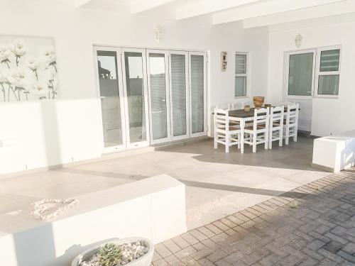 a white living room with a table and chairs at Lampies Bay Hideaway Close to the Shore in Stompneusbaai