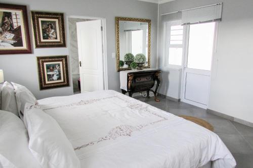 a bedroom with a white bed and a mirror at Lampies Bay Hideaway Close to the Shore in Stompneusbaai
