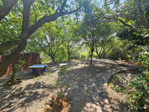 a picnic table and bench in a park with trees at Captans Stay in Lonavala