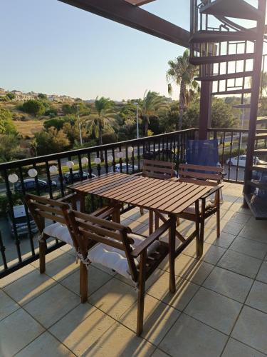 a wooden table and bench on a balcony with a view at Esuri Relax & Golf in Ayamonte