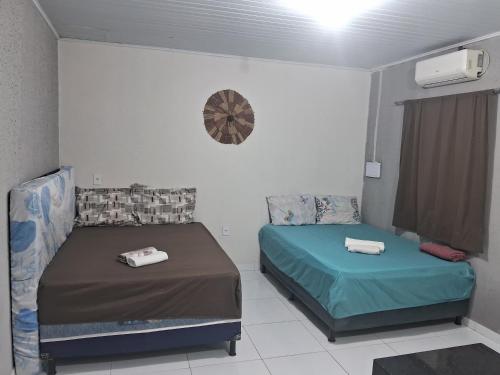 a bedroom with two beds and a clock on the wall at Casa Temporada, jequia in Jequia da Praia
