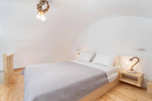 a bedroom with a bed with white sheets and a lamp at Santa Irini 2 in Vourvoúlos