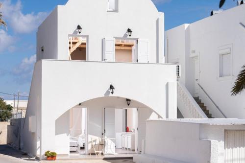 a white house with an archway in front of it at santairini in Vourvoulos