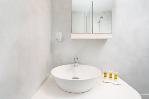 a white bathroom with a sink and a mirror at Santa Irini 2 in Vourvoúlos