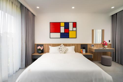a bedroom with a white bed and a painting on the wall at Coco villa in Hoi An