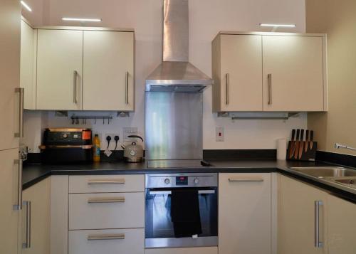 a kitchen with white cabinets and a stove top oven at Spacious Two Bedroom Hideaway in Wokingham with En Suite, Free Wi Fi and Parking, Sleeps Four in Wokingham