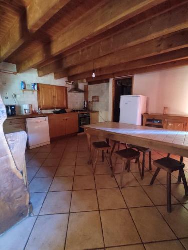 une cuisine avec une grande table et des chaises en bois dans l'établissement maison rénovée traditionnelle en chaume, à Kervignac