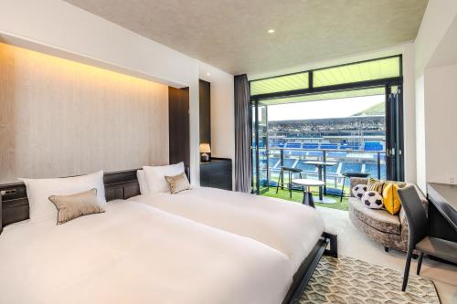 a bedroom with a large bed and a balcony at Stadium City Hotel Nagasaki in Nagasaki