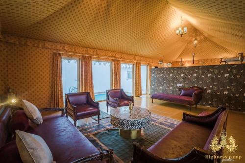 a living room with couches and a table and chairs at highness camp jaisalmer in Sām