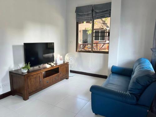 a living room with a blue couch and a tv at Villas Chalitaa วิลล่าชาลิตา in Chiang Mai