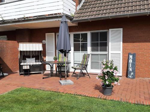 a patio with an umbrella and a table and chairs at Deichbrise in Greetsiel