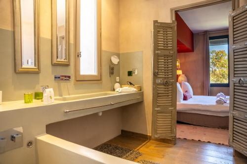 une salle de bain avec un lavabo, un miroir et un lit dans l'établissement LA VILLA, à Saint-Rémy-de-Provence