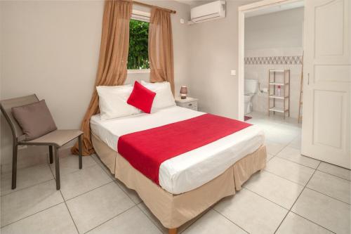 a bedroom with a bed with a red blanket and a chair at Villa Muscade - Maison avec piscine partagée in Saint-François