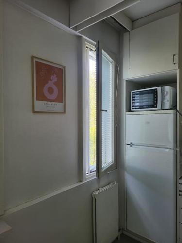 a kitchen with a refrigerator and a window and a microwave at Cozy apartment in Kemi City in Kemi