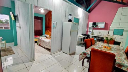 Una cocina con una mesa y un refrigerador en una habitación. en Apto com churrasqueira 500m do mar com vista da salaSacada para horizonte, en São Francisco do Sul
