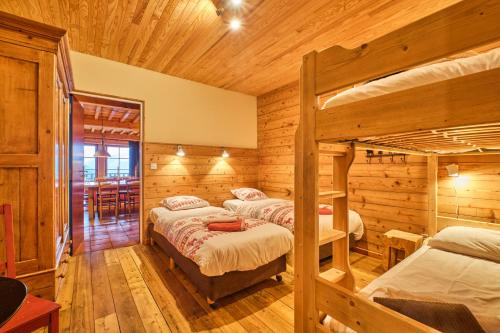 two bunk beds in a room with wooden walls at Chalet il fera beau demain in Villard-Reculas