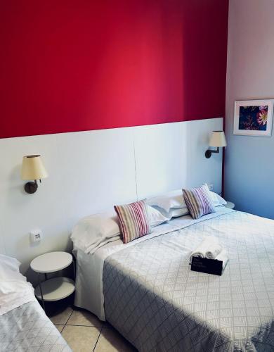 a bedroom with two beds and a red wall at Albergo Belsoggiorno in Sanremo
