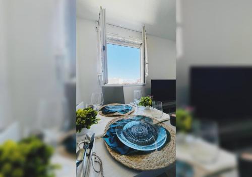 une table avec des assiettes et des verres bleus et une fenêtre dans l'établissement Le Cosy Zen Studio, à Valence