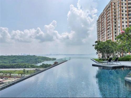 a large swimming pool with two chairs in front of a building at High Floor, 3BR 3queen bed, 2 parking, Urban Suites by XWHome in Jelutong