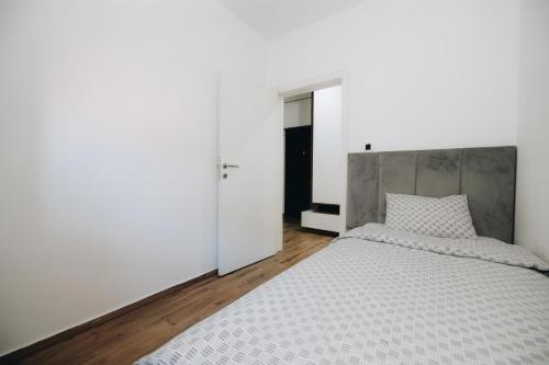 a bedroom with a large bed with a gray headboard at DUGA PARK lux in Kragujevac
