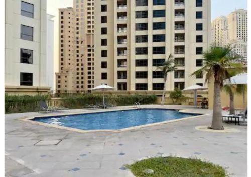 a swimming pool in front of a large building at Aesthetic Beach Apartment , Sleeps 6, Pool, Gym & Waterfront Views in Dubai