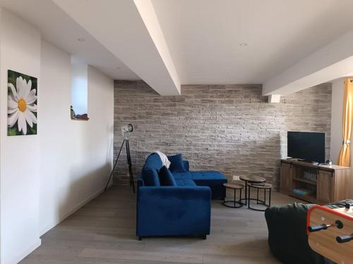 a living room with a blue couch and a brick wall at gîte des marguerites in Montigny-en-Morvan