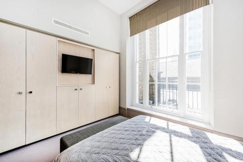 a bedroom with a bed and a tv and a window at Luxury Marylebone Apartment M1 in London