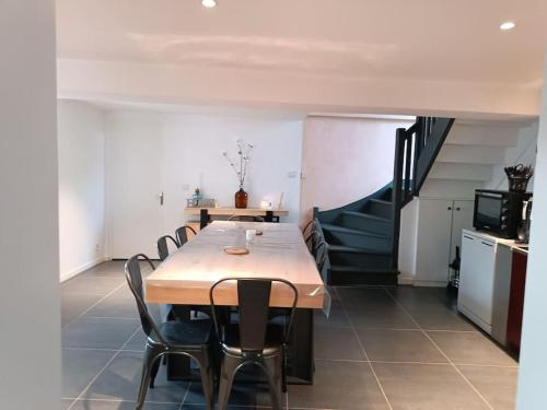 a dining room with a table and chairs and a staircase at gîte des marguerites in Montigny-en-Morvan